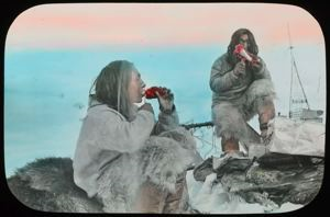 Image of Eskimos [Inuit] Cutting Meat Off at Lips